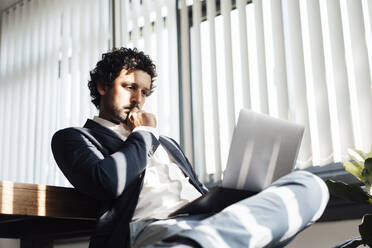 Businessman concentrating and working on laptop at office - JOSEF11835