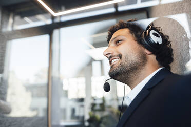 Lächelnder Geschäftsmann mit Headset im Büro - JOSEF11843