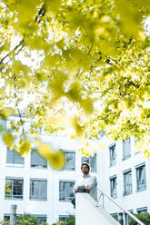 Businessman standing in front of office building - JOSEF11849