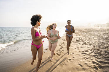 Happy multiracial friends running on shore at beach - OIPF02135