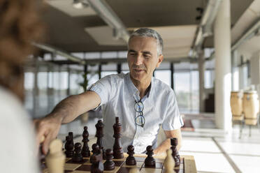 Reifer Geschäftsmann spielt Schach im Büro - JCICF00373