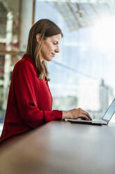 Geschäftsfrau arbeitet am Laptop am Arbeitsplatz - DIGF18480