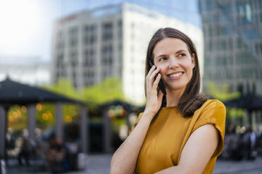 Lächelnde Geschäftsfrau, die mit einem Mobiltelefon spricht - DIGF18499