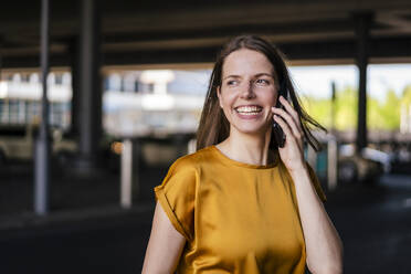 Fröhliche Geschäftsfrau, die mit einem Mobiltelefon spricht - DIGF18508