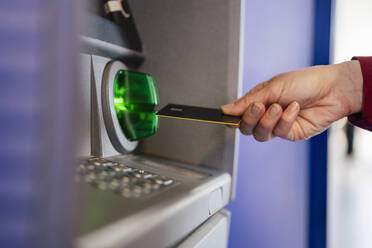 Frauenhand beim Benutzen einer Kreditkarte am Geldautomaten - DIGF18513