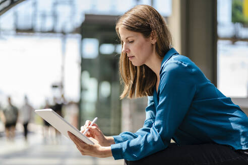 Businesswoman working on tablet PC with digitized pen - DIGF18539