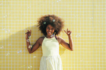 Glückliches Mädchen mit Afrofrisur gestikuliert Friedenszeichen - OIPF02213