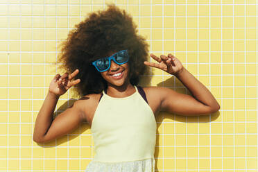 Smiling girl wearing sunglasses gesturing peace sign - OIPF02216