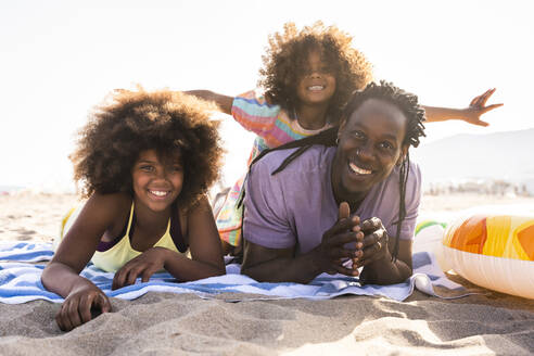Glückliche Töchter mit Vater am Strand liegend - OIPF02221