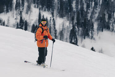 Skier wearing helmet and goggle standing on snow - OMIF01000
