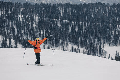 Mann mit ausgestreckten Armen hält Skistock auf Schnee - OMIF01002
