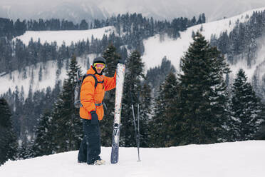 Skifahrer mit Ski und Stöcken vor einem Berg stehend - OMIF01010