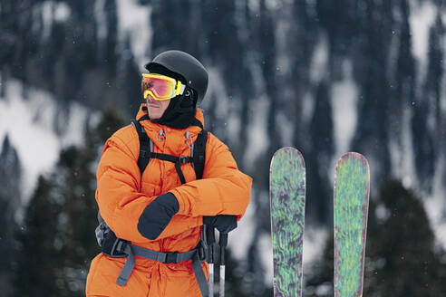 Skifahrer in warmer Kleidung, stehend mit Skiern und Stöcken - OMIF01015