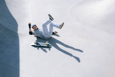 Skateboarder falling in skatepark on sunny day - OMIF01036