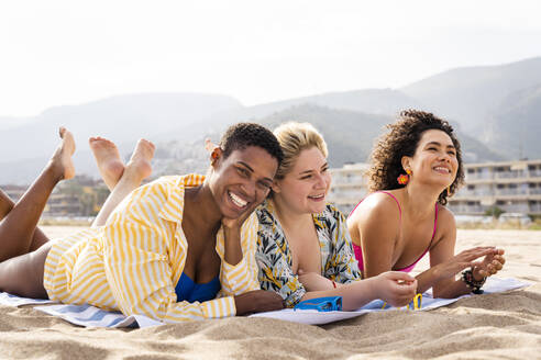 Glückliche multirassische Freunde, die im Urlaub am Strand liegen - OIPF02242