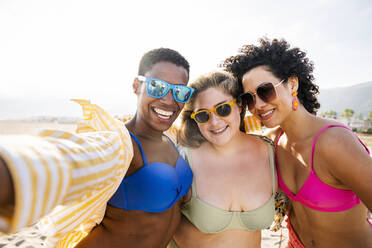 Multirassische Freunde mit Sonnenbrille machen ein Selfie am Strand - OIPF02265