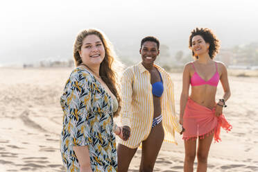 Smiling multiracial friends holding hands standing at beach - OIPF02276