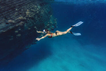 Woman swimming by shipwreck undersea - KNTF06747