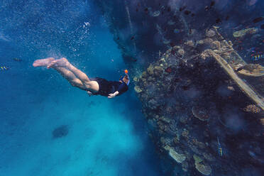 Man swimming on vacation by shipwreck in sea - KNTF06750