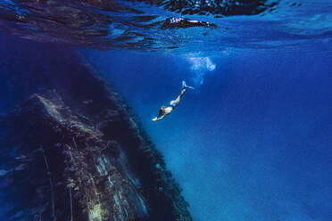 Woman diving underwater near shipwreck in sea - KNTF06755