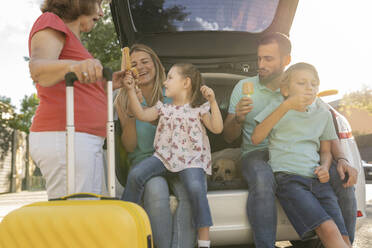 Glückliche Familie isst Eis auf dem Rücksitz eines Autos - JCCMF06788