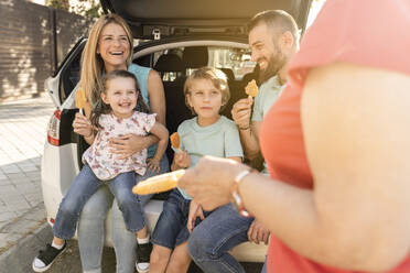 Glückliche Familie mit Eis am Stiel hinten im Auto - JCCMF06791