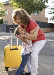 Cute girl embracing grandmother standing on road - JCCMF06792