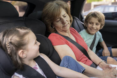 Geschwister betrachten die im Auto schlafende Großmutter - JCCMF06798