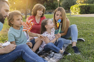 Familie spielt mit Windrädern beim Picknick im Park - JCCMF06805