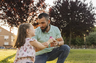 Father talking with daughter at park - JCCMF06822