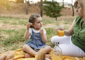 Girl talking with grandmother at park - JCCMF06834