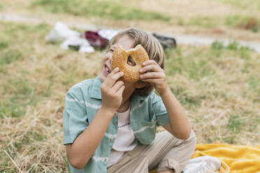 Boy looking through hole of bread - JCCMF06835