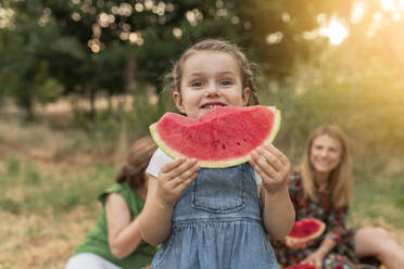 Cute girl holding watermelon standing at park - JCCMF06841