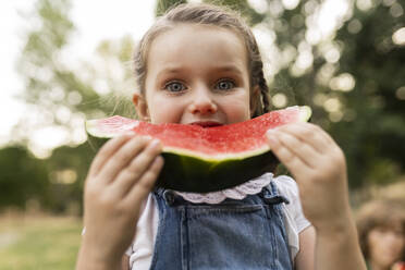 Nettes Mädchen isst Wassermelone im Park stehend - JCCMF06842