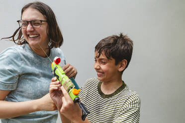 Glücklicher Sohn und Mutter, die mit einer Wasserpistole spielen - IHF01052