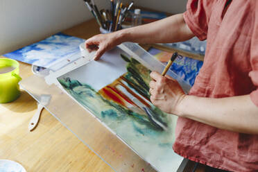 Artist with paintbrush painting on paper - IHF01060