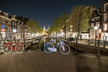 Niederlande, Nord-Holland, Amsterdam, Fahrräder links entlang der Grachtenbrücke bei Nacht - WPEF06255