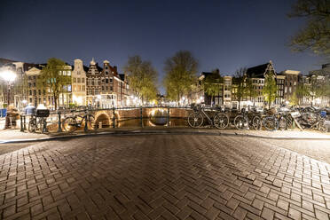 Niederlande, Nord-Holland, Amsterdam, Fahrräder links entlang der Grachtenbrücke bei Nacht - WPEF06257