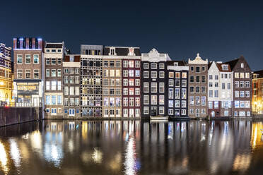 Netherlands, North Holland, Amsterdam, Long exposure of Damrak canal at night with rowhouses in background - WPEF06261
