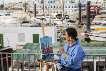 Frau malt auf Staffelei am Hafen - IHF01074