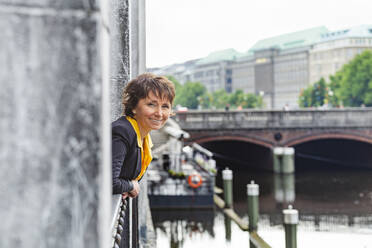 Smiling mature woman leaning out of window - IHF01088