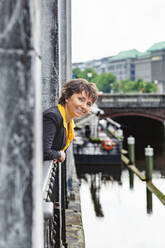 Smiling woman leaning out of window - IHF01089