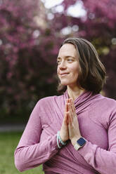 Lächelnde Frau mit verschränkten Händen, die Yoga praktiziert - EYAF02002