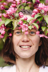 Happy woman amidst pink apple blossoms - EYAF02014