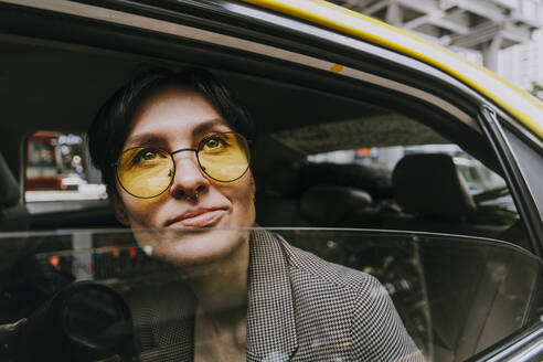 Nachdenkliche Geschäftsfrau mit gelber Sonnenbrille im Auto sitzend - OIPF02284