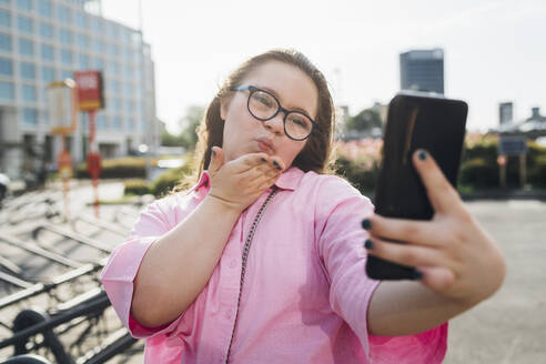 Teenager-Mädchen bläst Kuss und nimmt Selfie auf Handy - MEUF07352