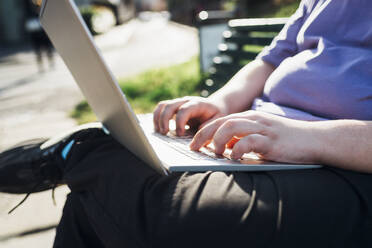 Hands of teenage boy using laptop in park - MEUF07371