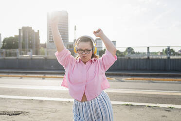 Teenager-Mädchen mit Kopfhörern hört Musik und tanzt auf der Straße - MEUF07378