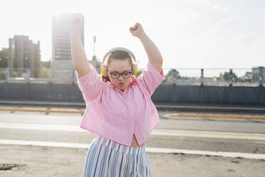 Teenage girl wearing headphones and dancing on street - MEUF07379