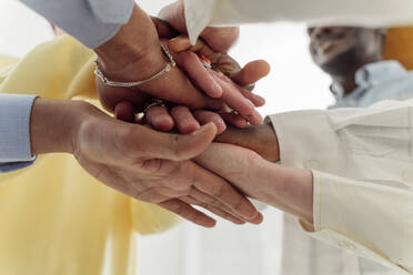 Colleagues stacking hands together in team building training - OSF00556